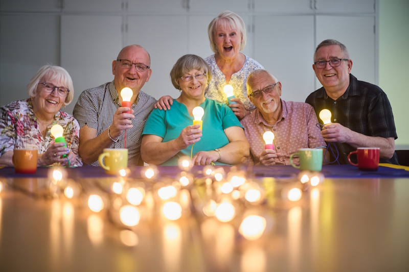 Members Holding Glowing Lightbulbs Web