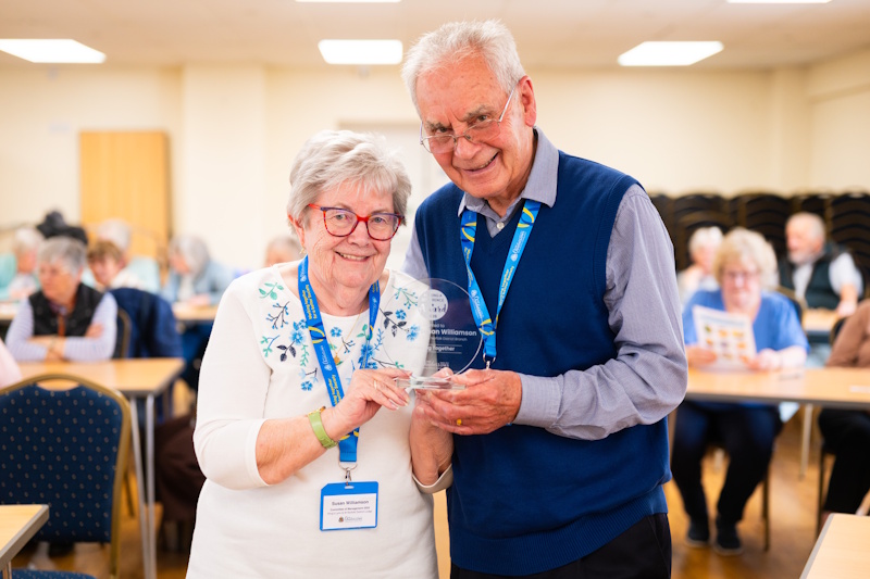 A woman and a man holding a glass trophy together