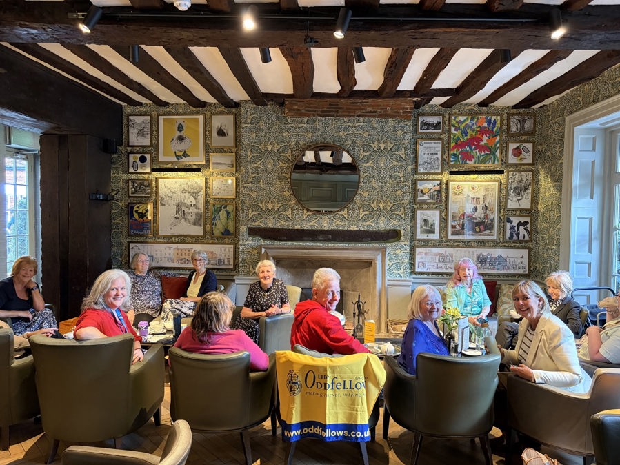11 members getting together to catch up over coffee. They are sat in comfy chairs and looking at the camera and smiling