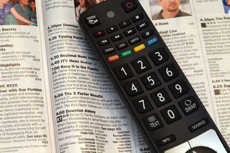 Remote control sat on top of a tv listings magazine