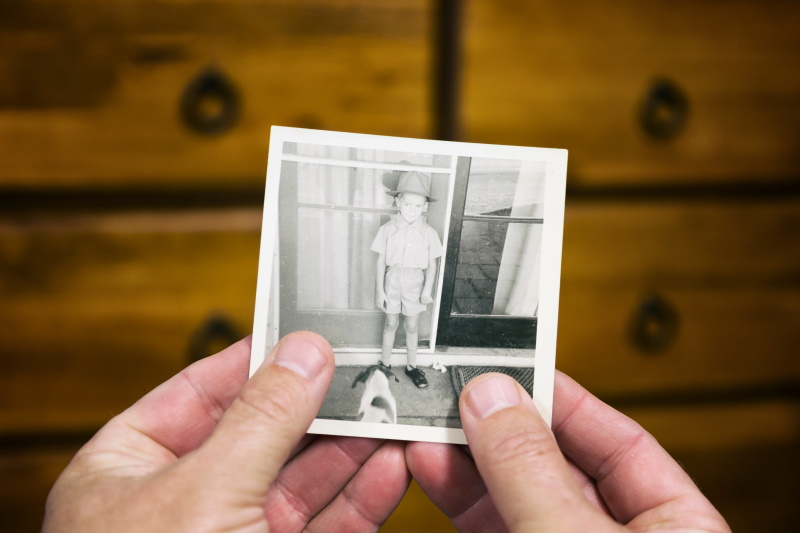 Person looking at an old photo of a boy