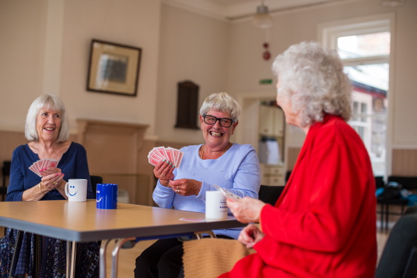 Three ladies having fun playing cards round a table.