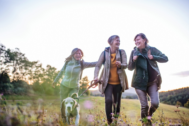 Three older woman out on a dog walk, laughing and smiling together
