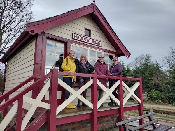 Four women stand on an old train platform