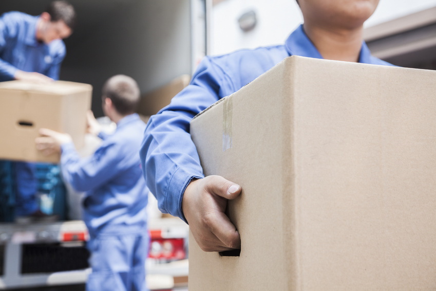 Three men carrying boxes off a home removals van