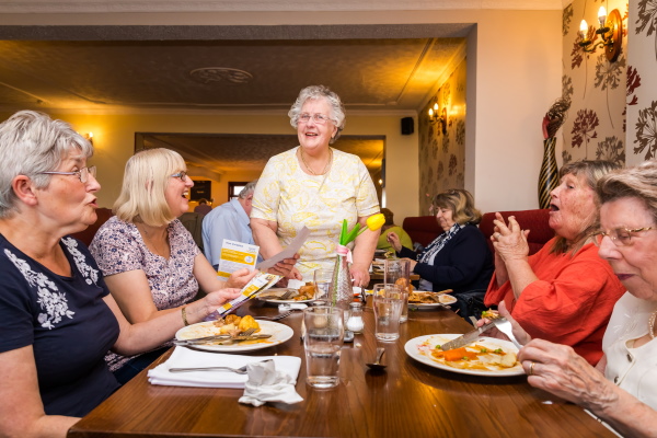 A group of ladies chatting and laughing around a table