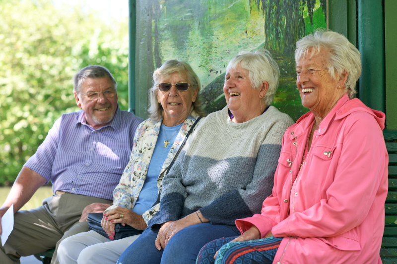 Julie sat on a bench with two female and one male friend smiling