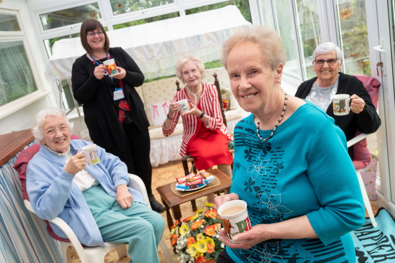 Christine enjoying a cup of tea with her friends in her conservatory.