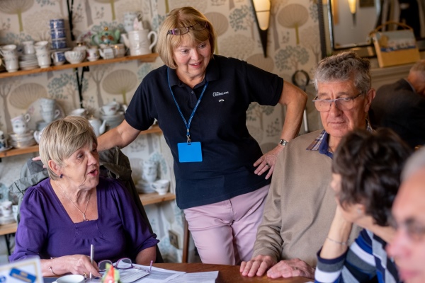 An Oddfellows member volunteer chatting to a group of people at a coffee morning