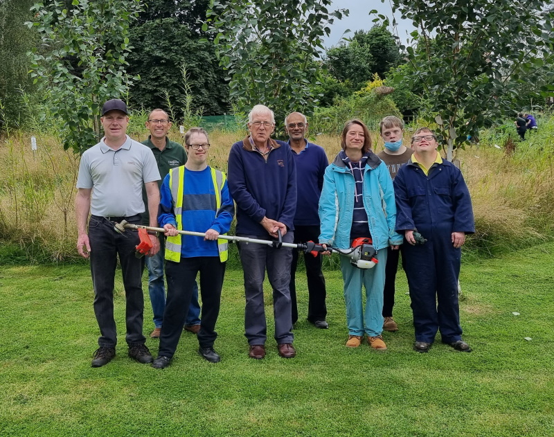 A line up of people at the community gardens showing off the new strimmer