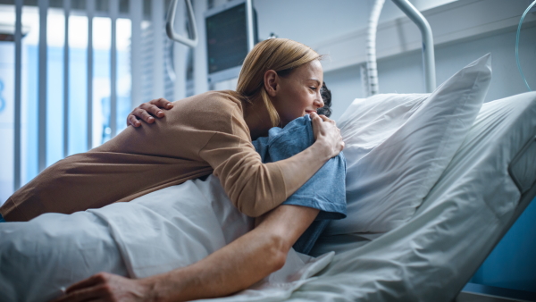 Woman hugging a male patient in a hospital bed