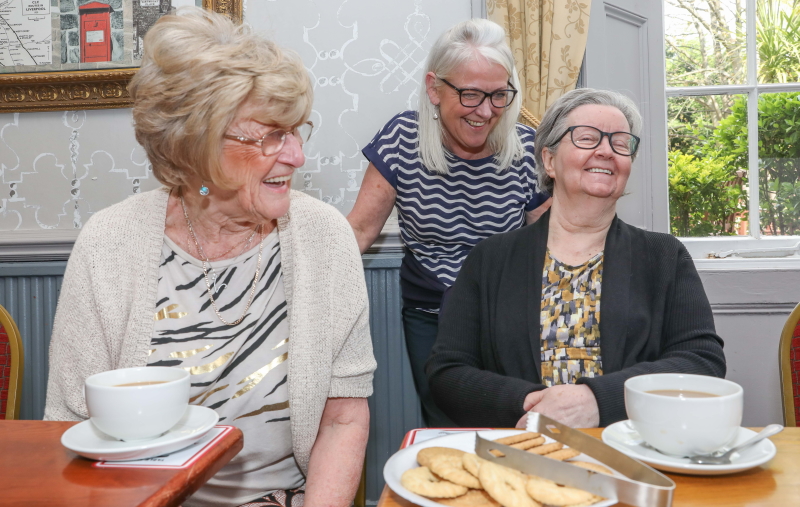 Val Rider with two friends at one of the Oddfellows' meet-ups. Laughing and enjoying a cup of tea and some biscuits