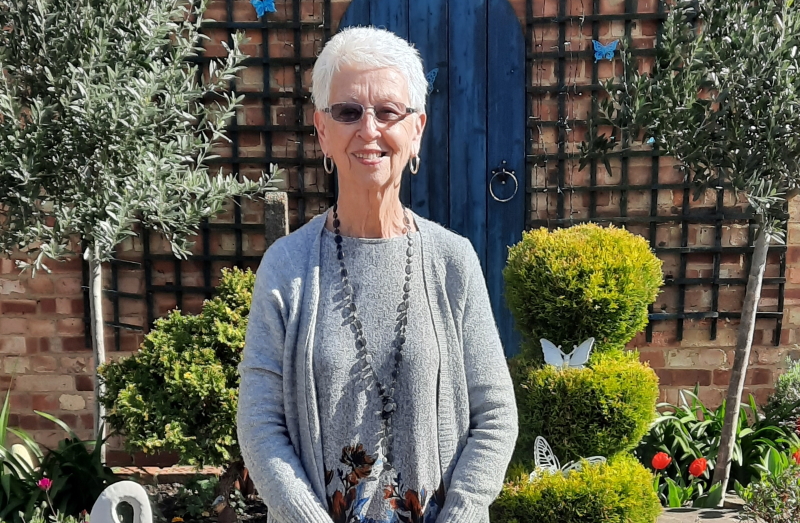 Award-winner Sylvia stood smiling at the camera with a beautiful garden in the background