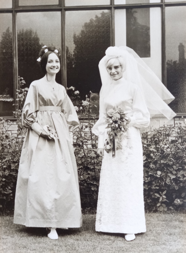 Madeline and Sandra stood together at Sandra's wedding. Madeline is in her bridesmaid dress and Sandra in her wedding dress holding her bouquet - back at her wedding 1969