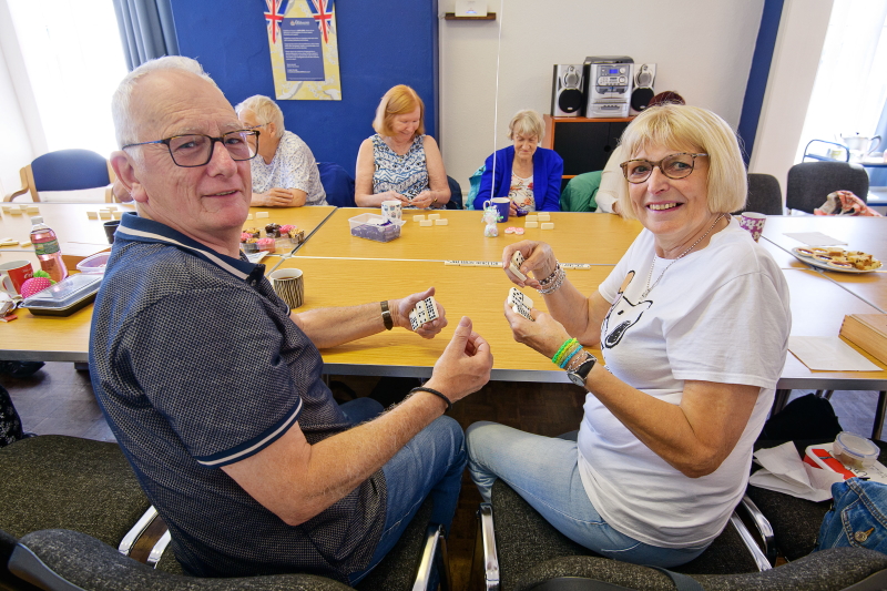 Group of members sat round a table playing Dominoes