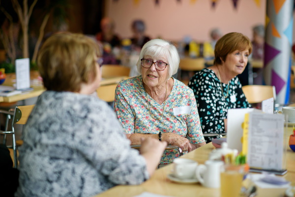 Three ladies sitting along a table talking to each other