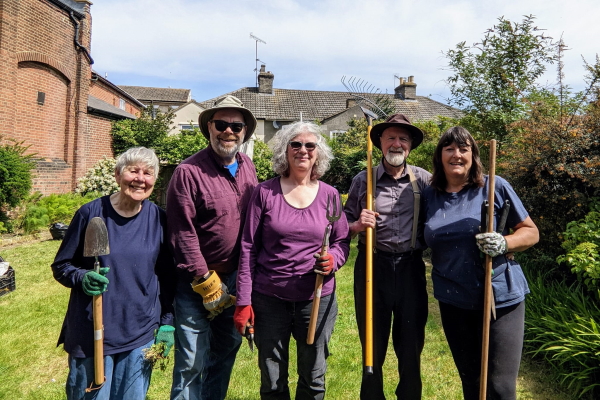 A row of 5 members, including Kevin and Teresa, outside in their gardening gear.