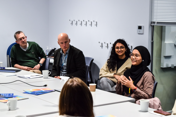 Professor Edd James, Dr Tim Fenton and Donor Relations Officer Asha Ellis sitting at a table listening to Nur Zainal speak about her research
