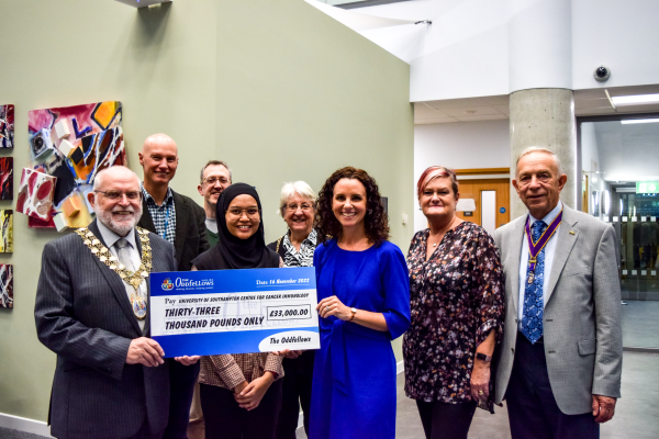 A group of people from the Oddfellows and the Centre for Cancer Immunology pose for the camera holding a large cheque