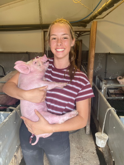 Ava Craven cuddling a pink piglet