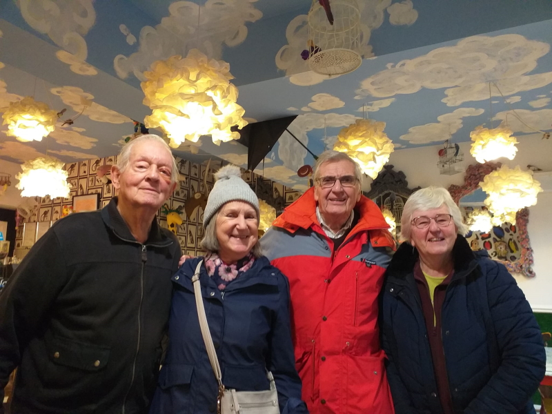 Two men and two women stood together smiling after a walk in a cafe