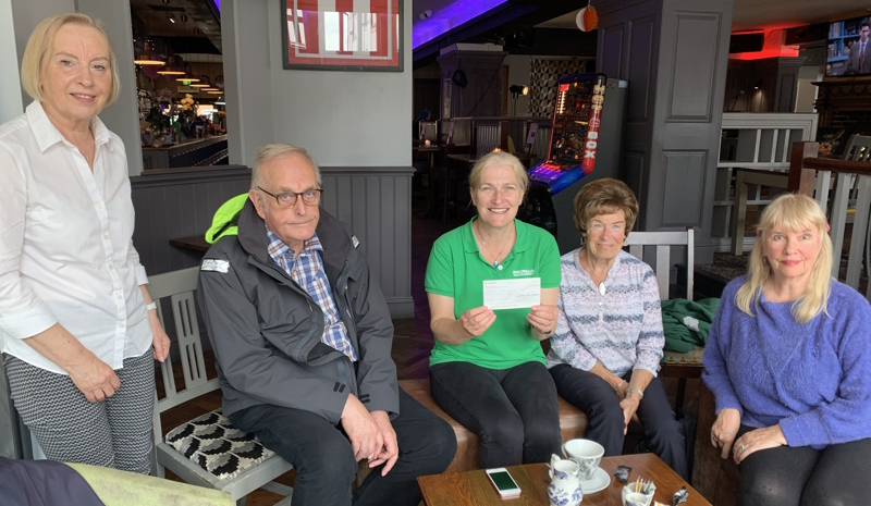 Four members and a representative from the charity grouped together with a cheque.