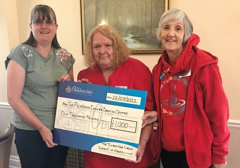 Three representatives from the Oddfellows and the charity holding a big cheque together.