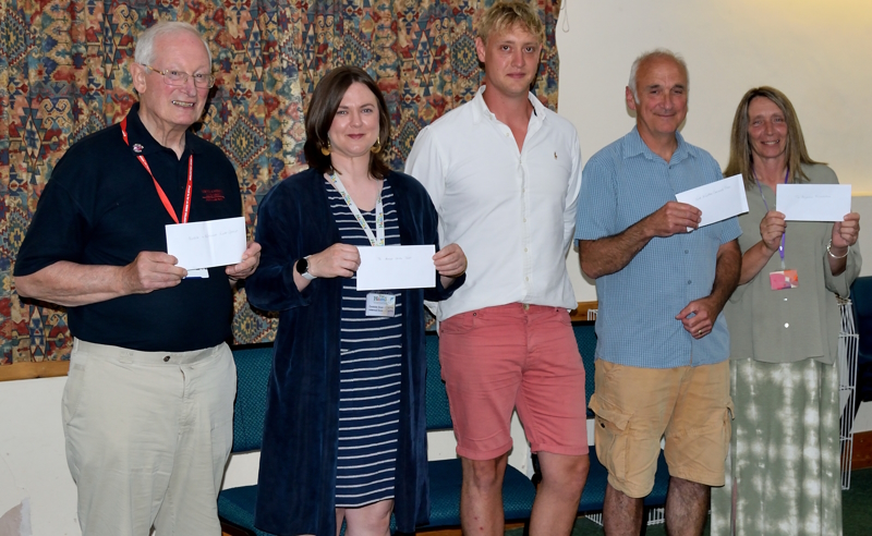 Five representatives from the charities and oddfellows stood in a line holding their cheques.