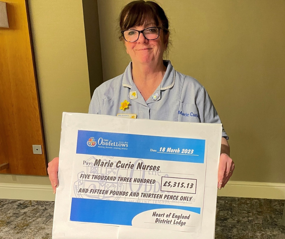 Marie Curie Nurse Anne Curry smiles as she holds up a cheque for £5,315.13 from the Oddfellows Heart of England District Lodge