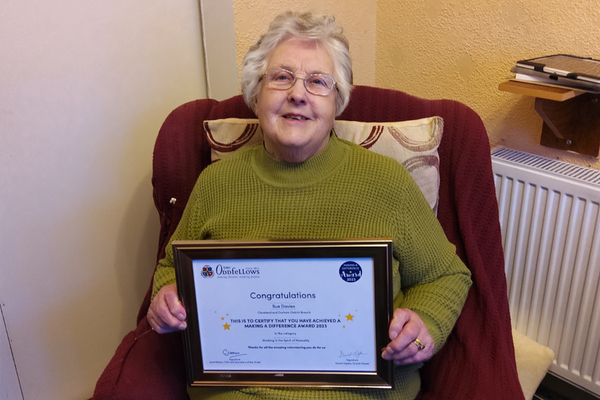 Sue Davies smiles while holding a framed certificate of her award