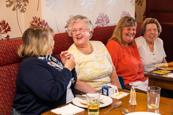 Four women laughing round a table