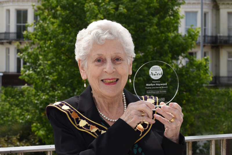 Marilyn Hayward smiles while holding up her trophy