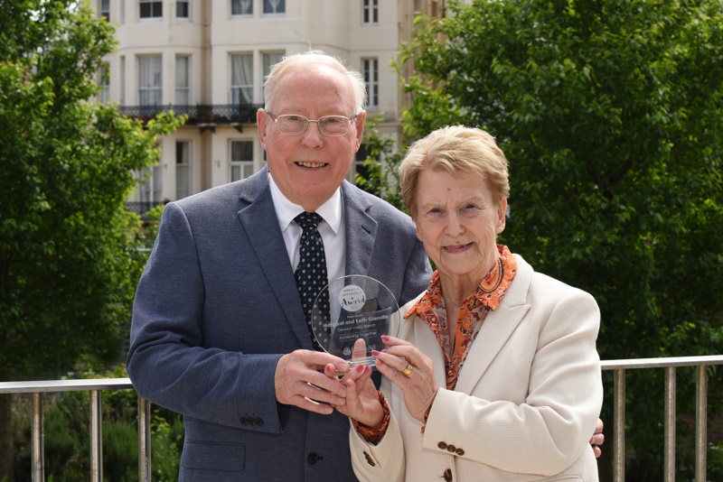 Keith and Margaret stand smiling together, both holding their trophy