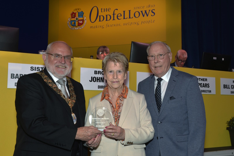 Margaret and Keith being presented with their trophy on stage  by the Society's Chairman, David Ogden