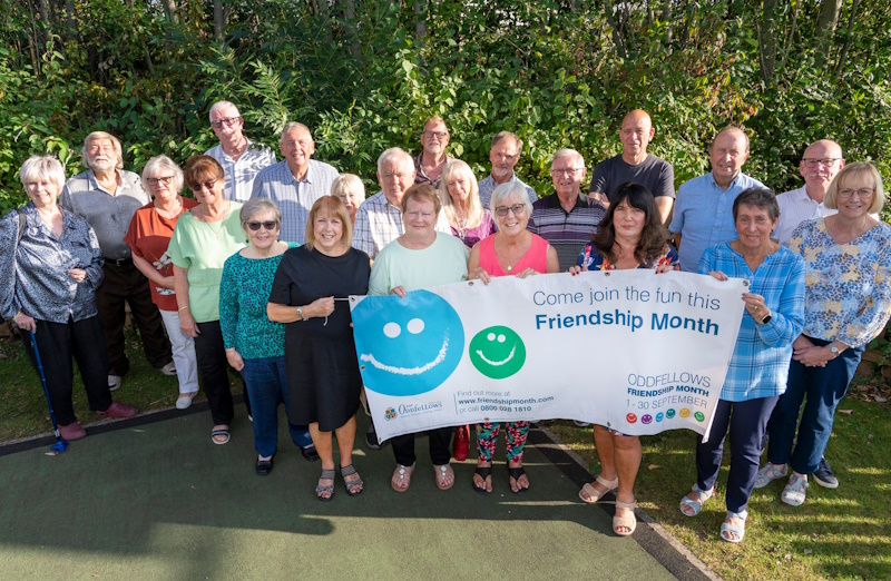 A big group of people holding a Friendship Month banner