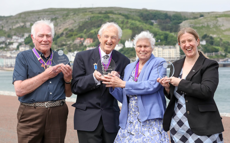 Four people smiling and holding their awards