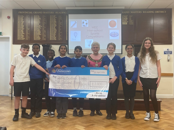 Children and a woman smile at the camera holding a cheque