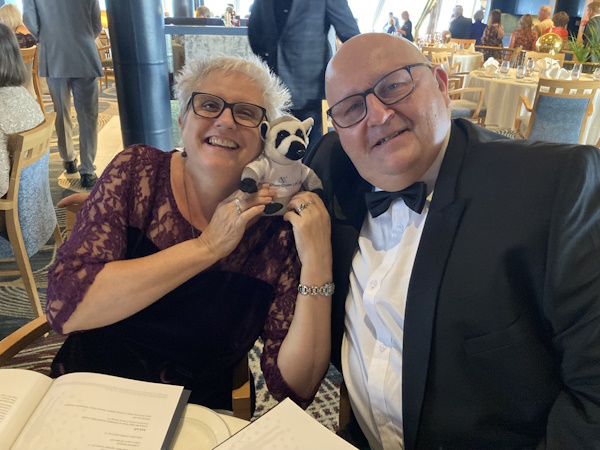 A woman and a man dress formally while holding a toy lemur