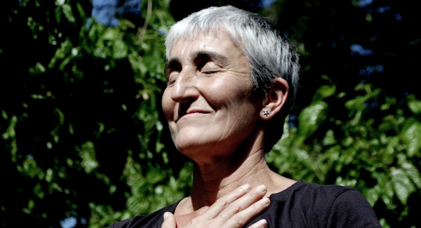 A woman with her eyes closed and hand on her chest, smiling