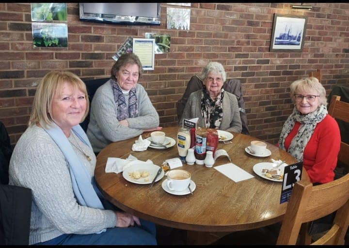 Four women sitting around a table smiling to the camera