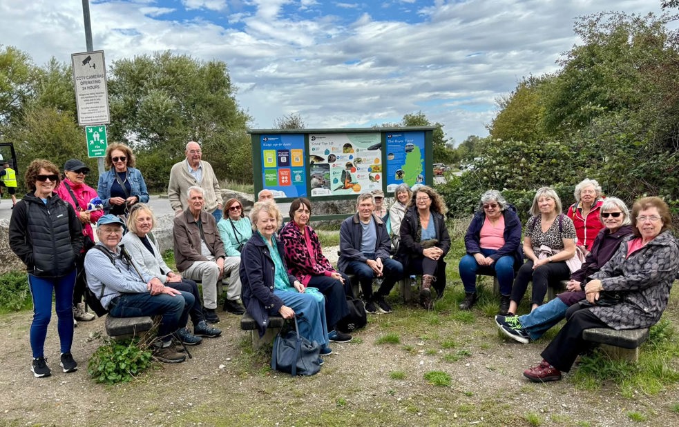 A group of 20 members sat taking a break outdoors during a group walk