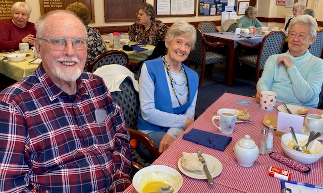 Three people smile for the camera as they sit around a table