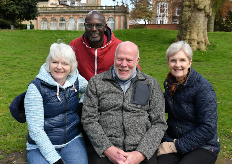 Pete sat on a bench in a park with three other Oddfellows members. All are smiling