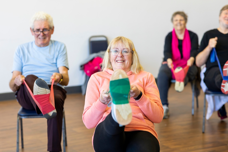 Four people taking part in a low impact exercise using resistance bands