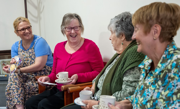 Four women laughing and smiling together