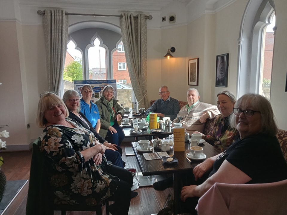 Eight members of Deeside Oddfellows sat around a table enjoying refreshments