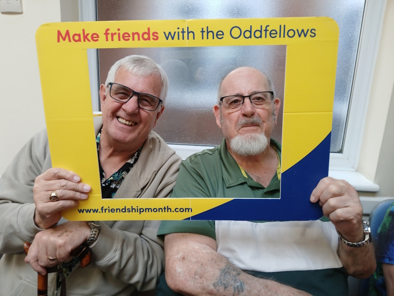 Two men smiling with a frame around their faces which says 'make friends with the Oddfellows'