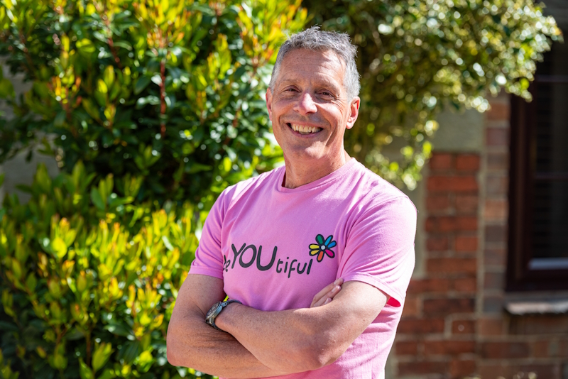A head and shoulders photo of Dr Andy Cope. He's stood smiling with crossed arms