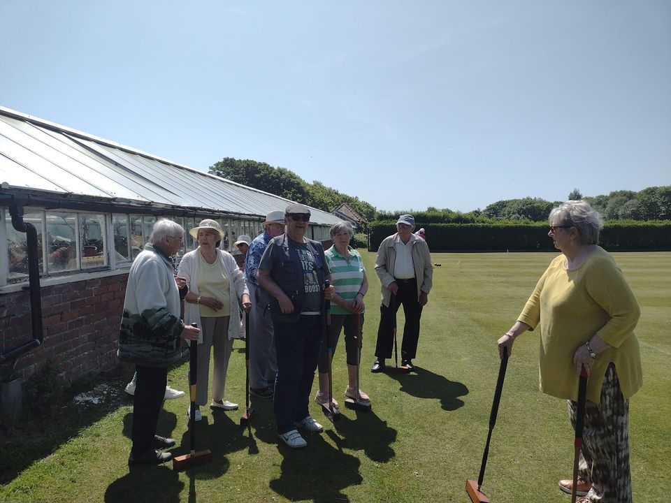 A group of people holding croquet mallets on a pitch