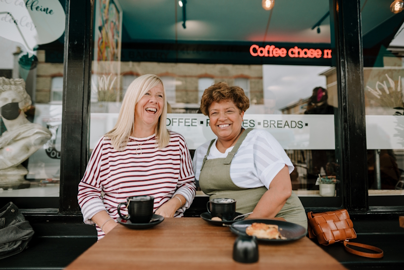 Two women outside a cafe enjoying having a coffee together